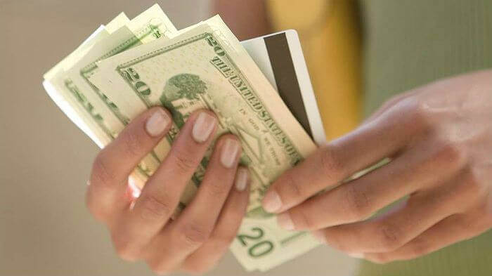 woman's hands hold cash and credit card