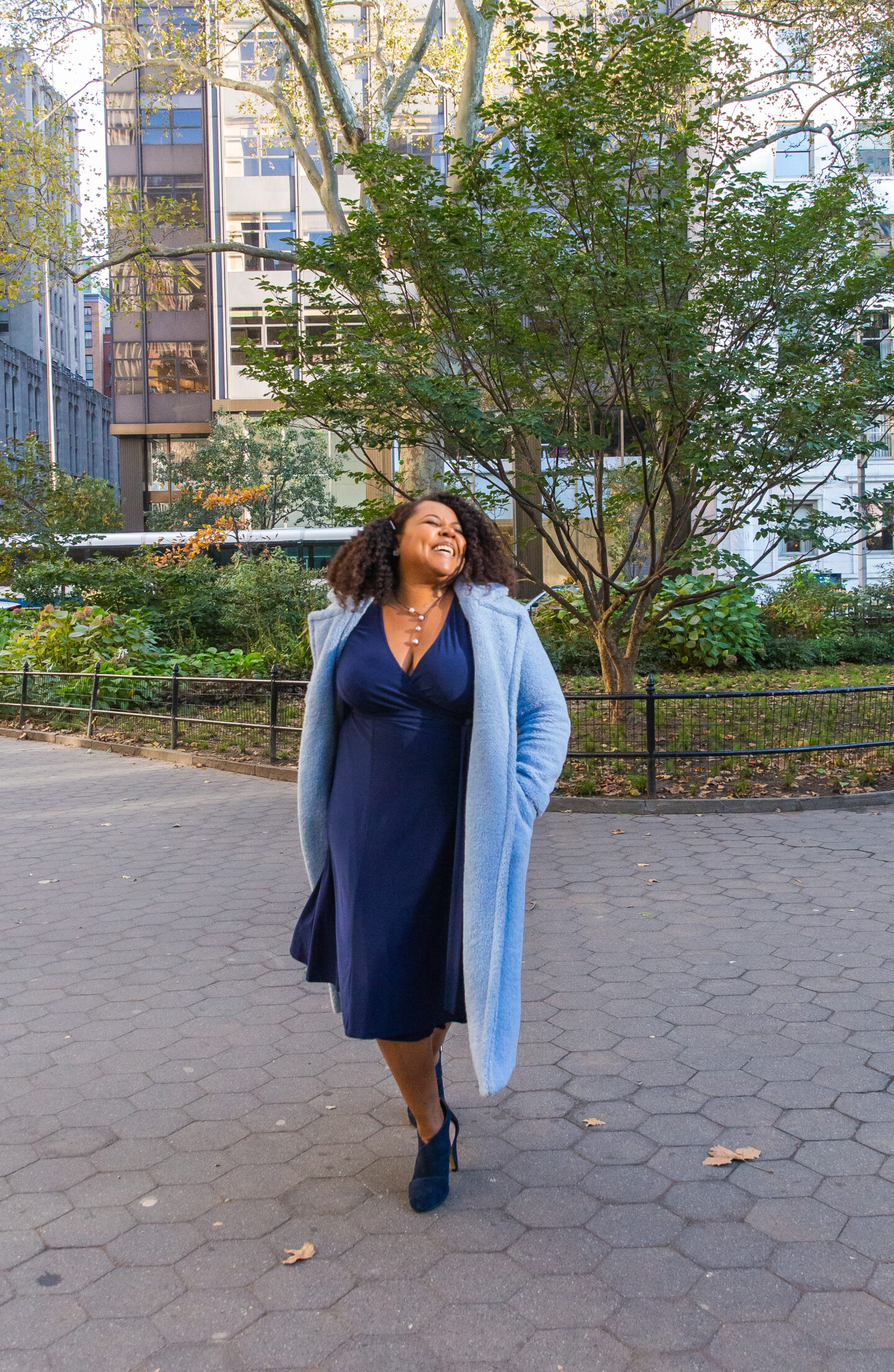 patranila walks in madison square park wearing blue dress and coat