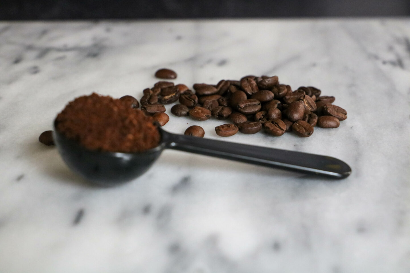 rich kona coffee beans with scoop of grounds