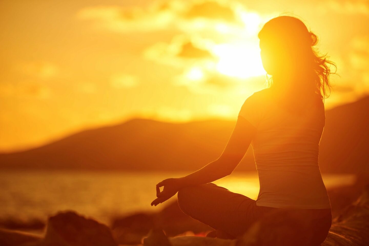 woman meditating at sunset