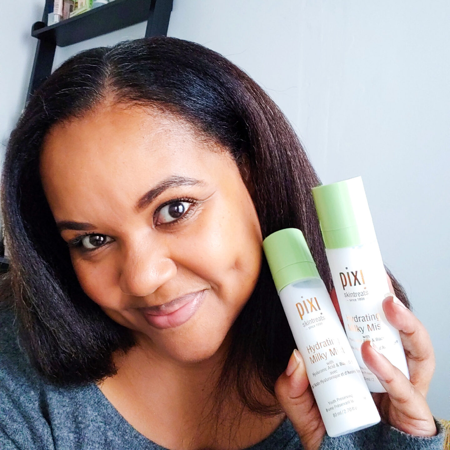 Patranila holds two bottles of Pixi Beauty Hydrating Milky Mist for extra dry skin in winter.