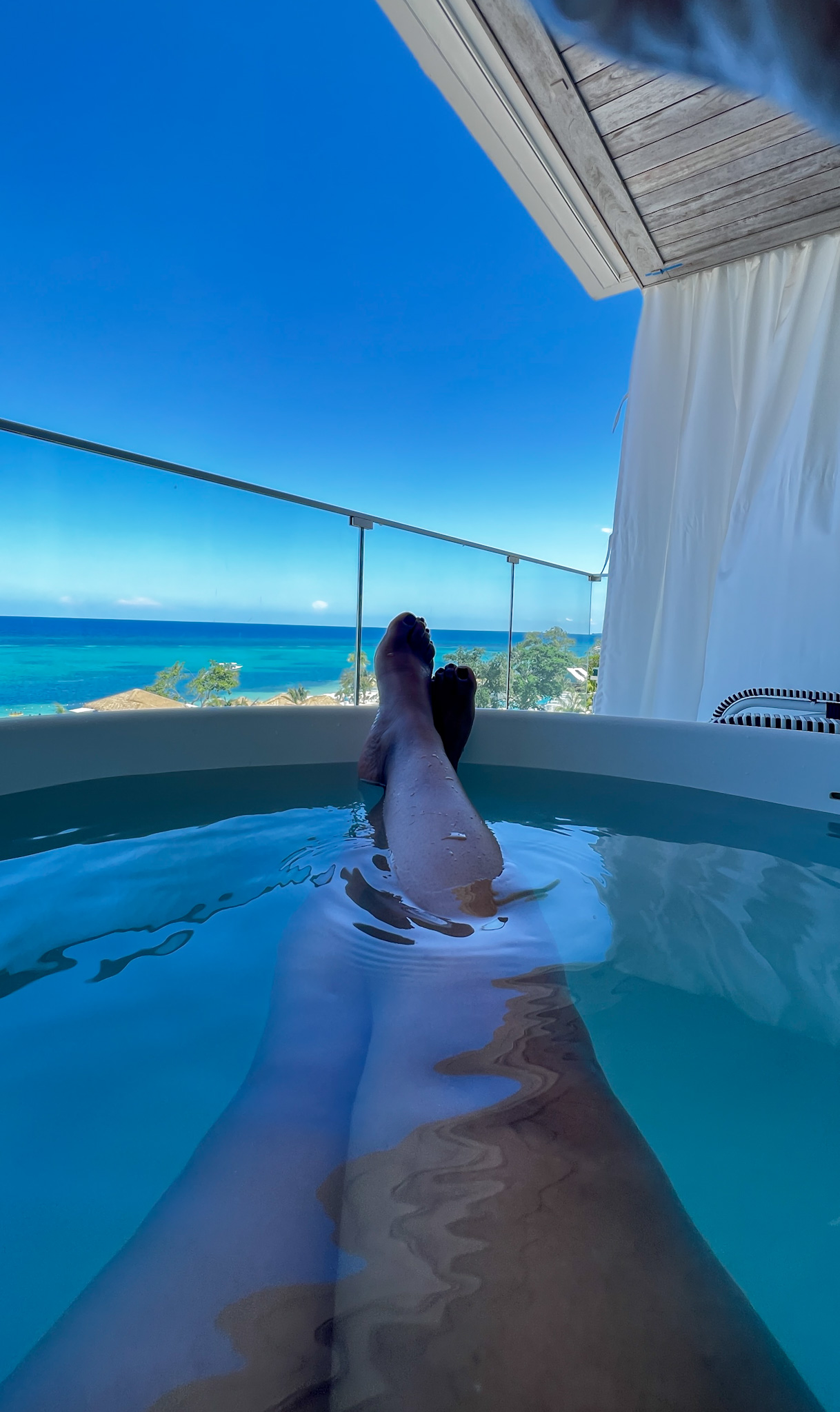 patranila's legs in a tub on a balcony overlooking the sea
